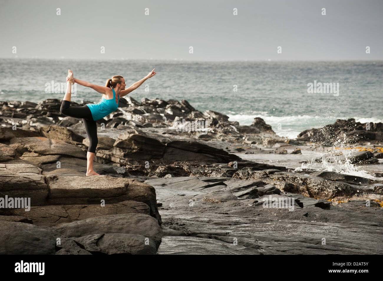 Woman practicing yoga on rock formation Banque D'Images