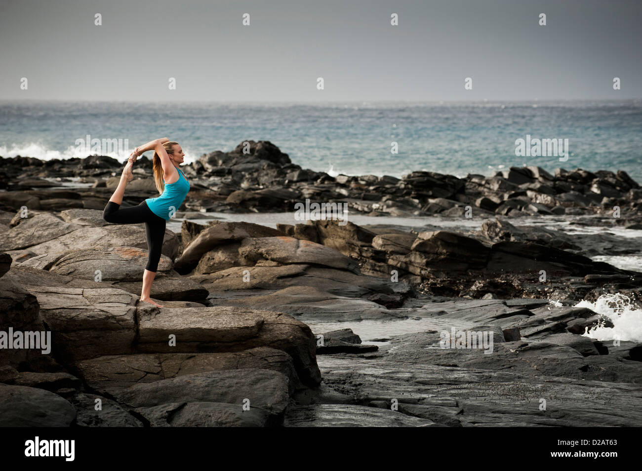 Woman practicing yoga on rock formation Banque D'Images