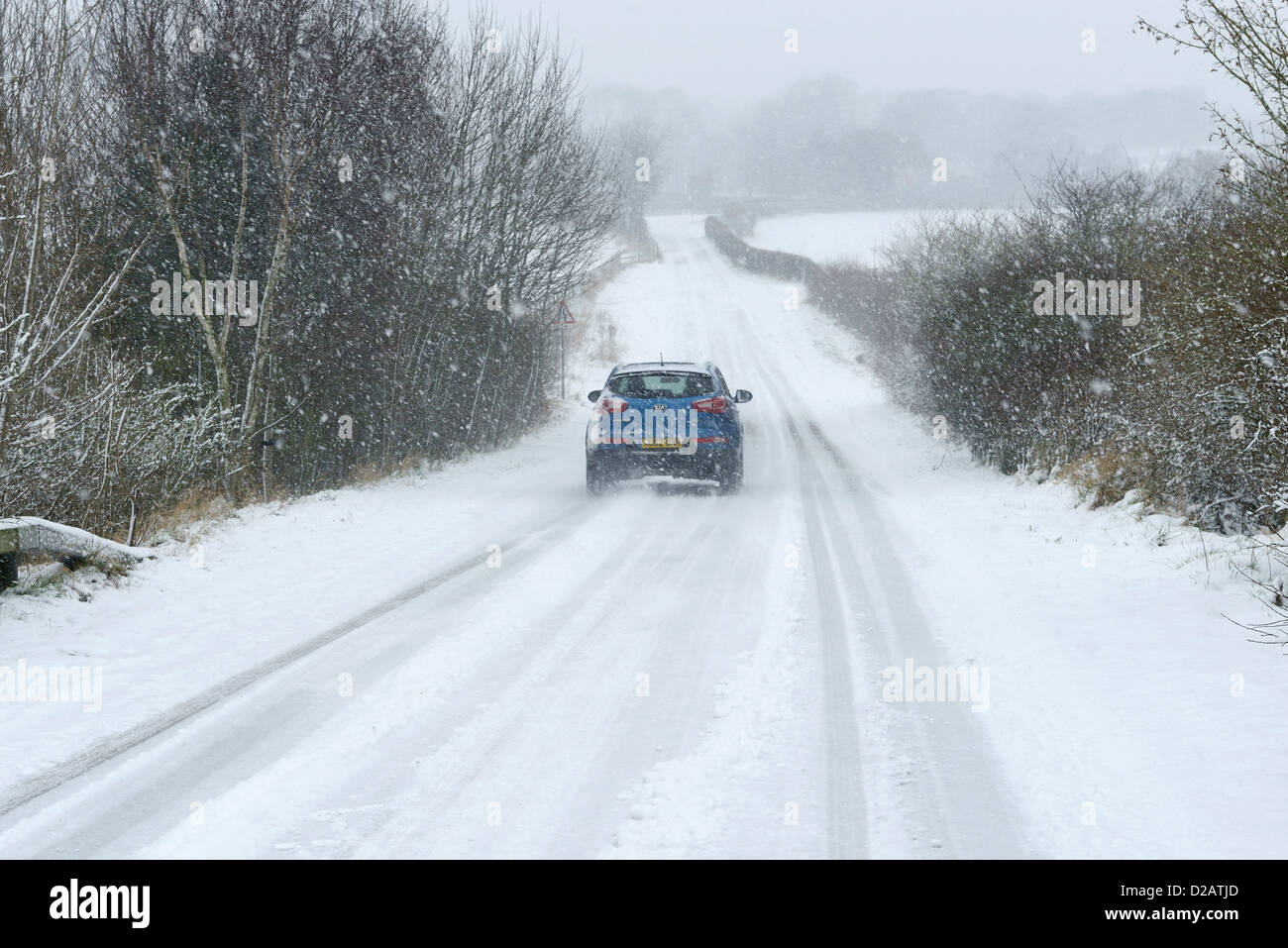 Une voiture se déplace le long d'une route couverte de neige dans la région de Chester UK Banque D'Images