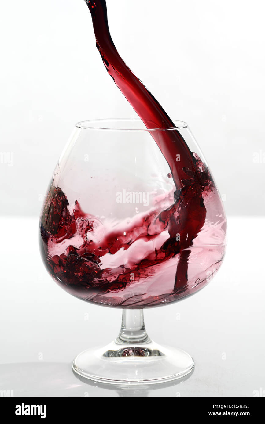 Port étant versé dans un petit verre en verre sur un fond blanc Photo Stock  - Alamy