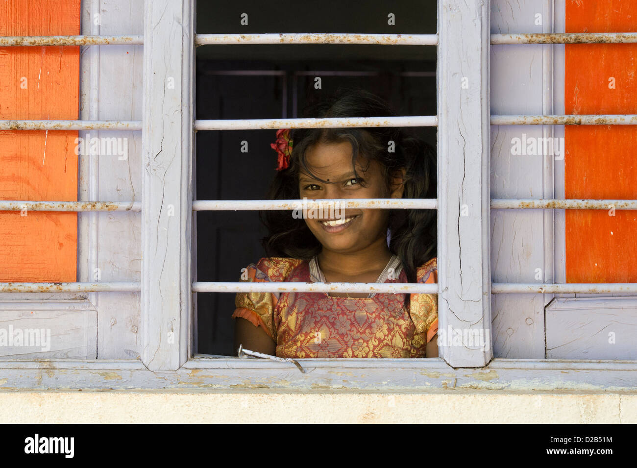 Jeune Indien village girl looking through window bars dans une maison indienne. L'Andhra Pradesh, Inde Banque D'Images