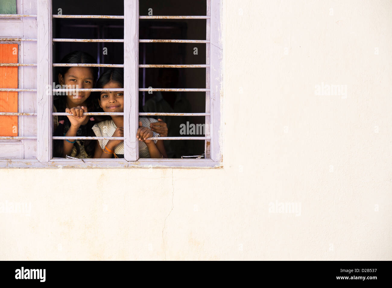 Les jeunes filles du village indien à la fenêtre à travers les barreaux d'une maison indienne. L'Andhra Pradesh, Inde Banque D'Images