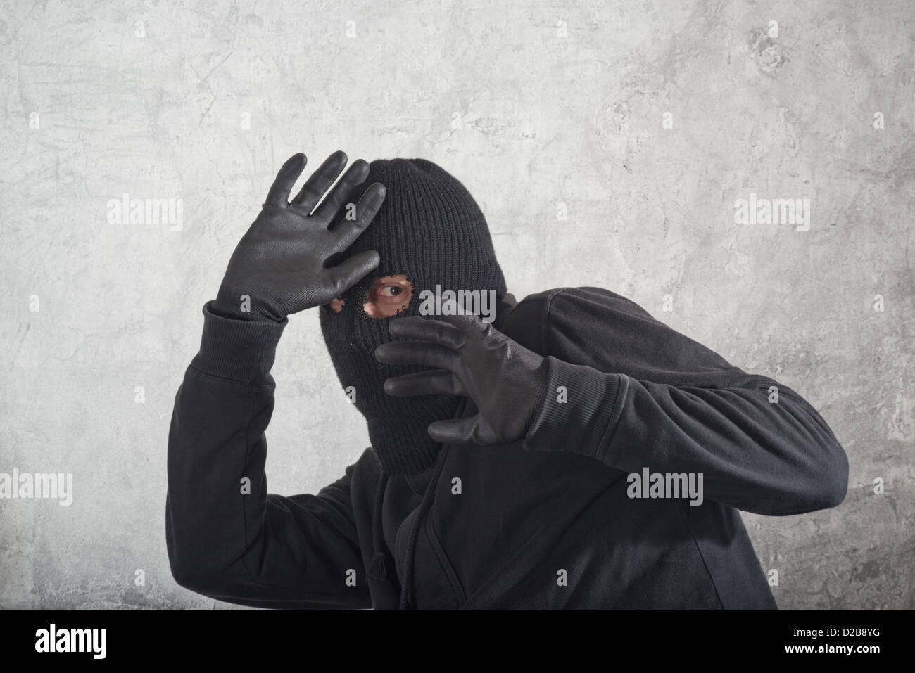 Attraper le voleur, voleur concept avec balaclava pris en face de l'grunge mur de béton. Banque D'Images