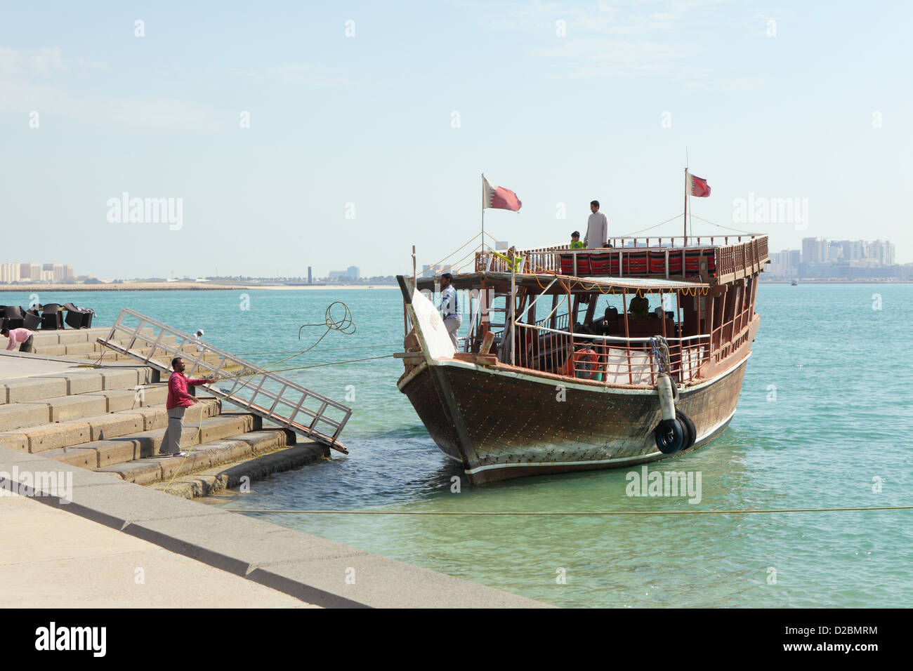 Un travailleur à terre jette une corde à son second d'un boutre de plaisir comme elle sur la Corniche des Maures dans la baie de Doha, au Qatar. Banque D'Images