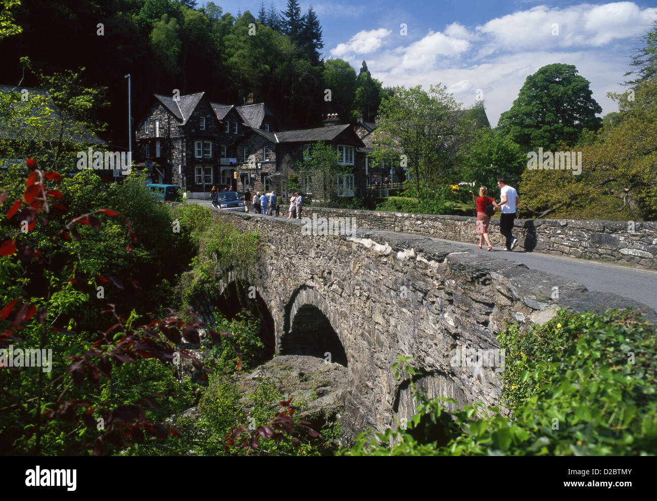 Personnes marchant sur Pont-a-paire pont de pierre Betws-Y-Coed Conwy County Parc National de Snowdonia North Wales UK Banque D'Images