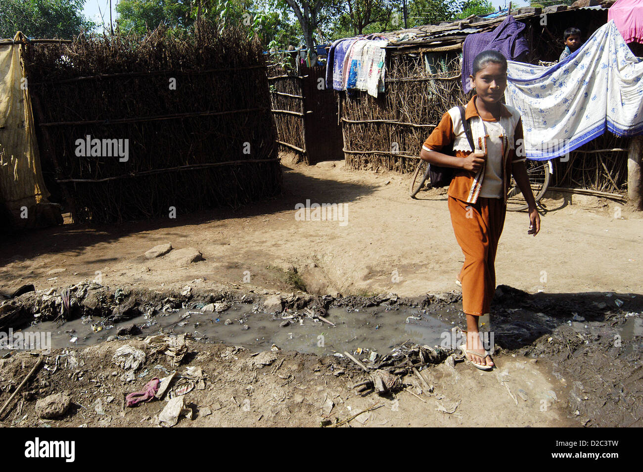 Indian Girl Walking Through Open Drain d'égout en raison de l'assainissement dans les villages très pauvres villageois tombent souvent malade maux divers dans Banque D'Images