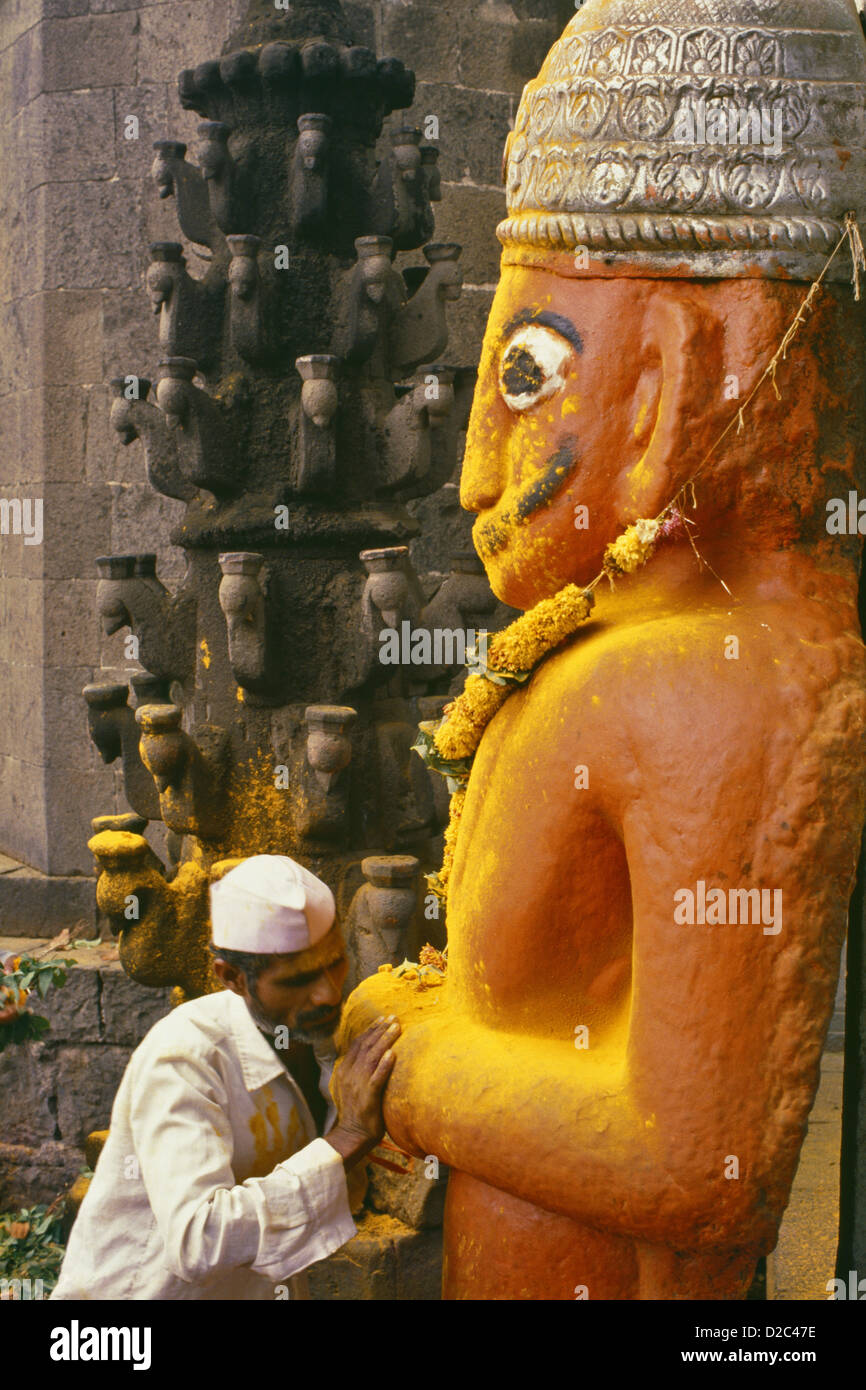 Adorant la douche Poudre de curcuma jaune sur un grand démon Statue Orange-Red Malla qui avaient converti dévot démon Khandoba Banque D'Images