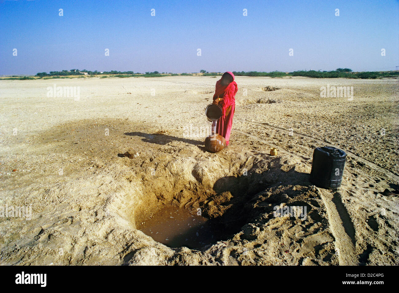 L'eau est recueillie à partir d'un trou peu profond creusé dans le lit de la rivière séchés par femme, l'ouest du Rajasthan, en Inde. Banque D'Images