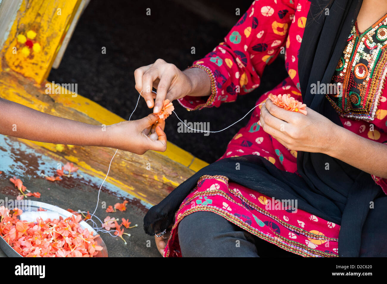 Les filles indiennes faisant une guirlande de fleurs à l'extérieur d'une maison de village. L'Andhra Pradesh, Inde Banque D'Images