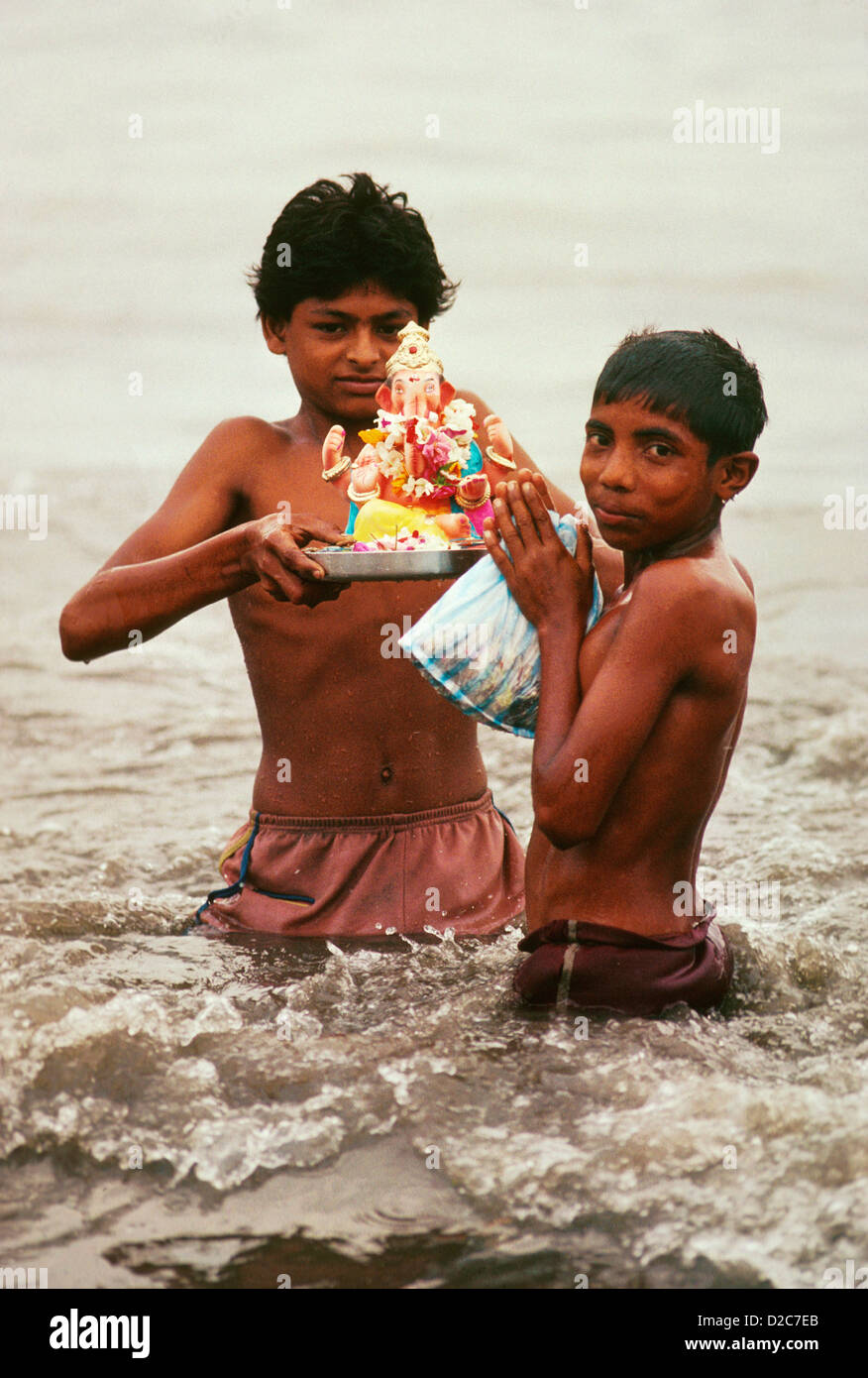 L'Inde, deux garçons dans l'eau, en maintenant la figure de Ganesh. Au cours du Festival Ganesh Banque D'Images