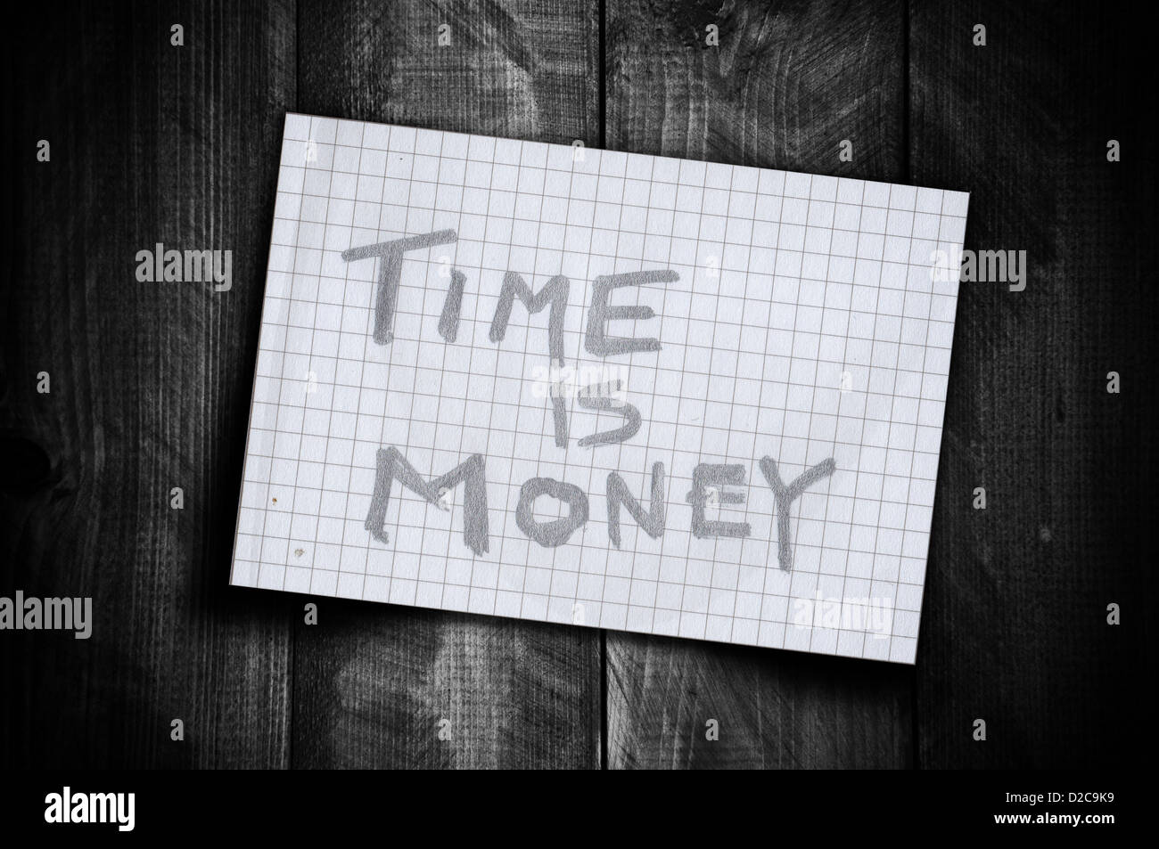 Note de rappel 'time is money' sur une feuille de papier sur un vieux fond de bois. Banque D'Images