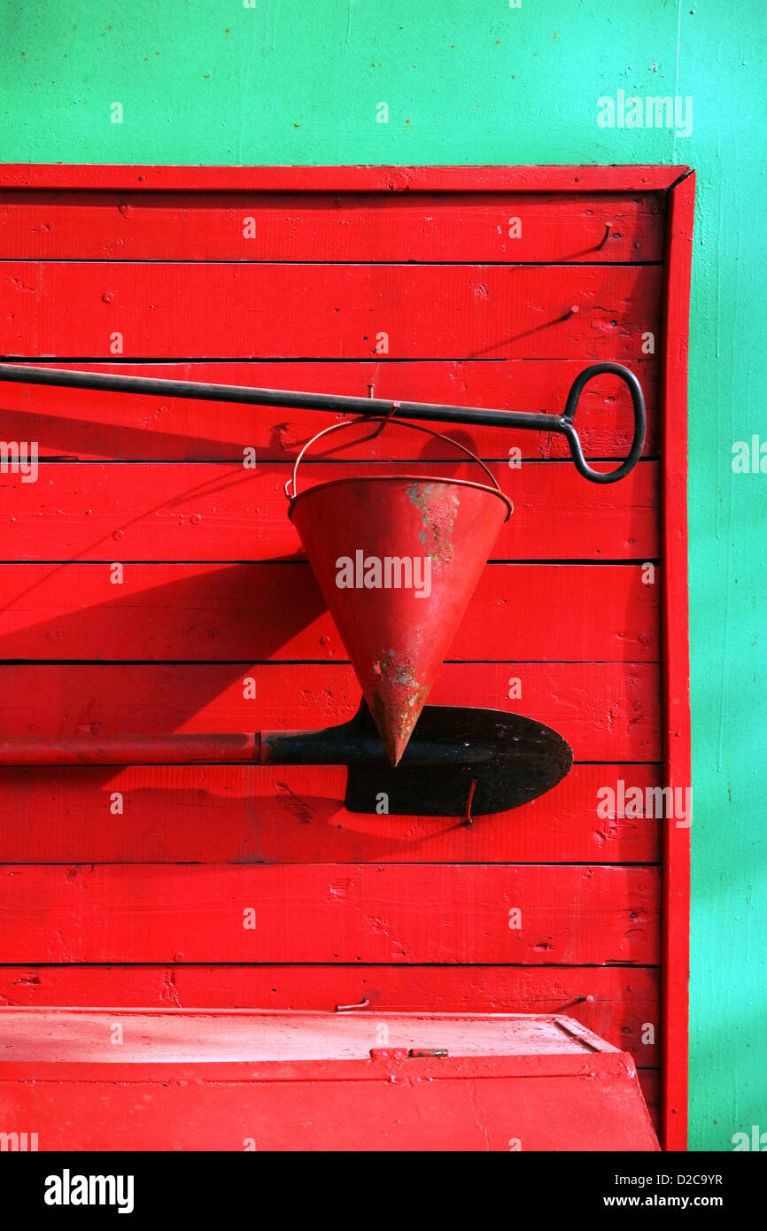 Godet, une pelle, un bris contre un vieux hangar rouge en bois Banque D'Images