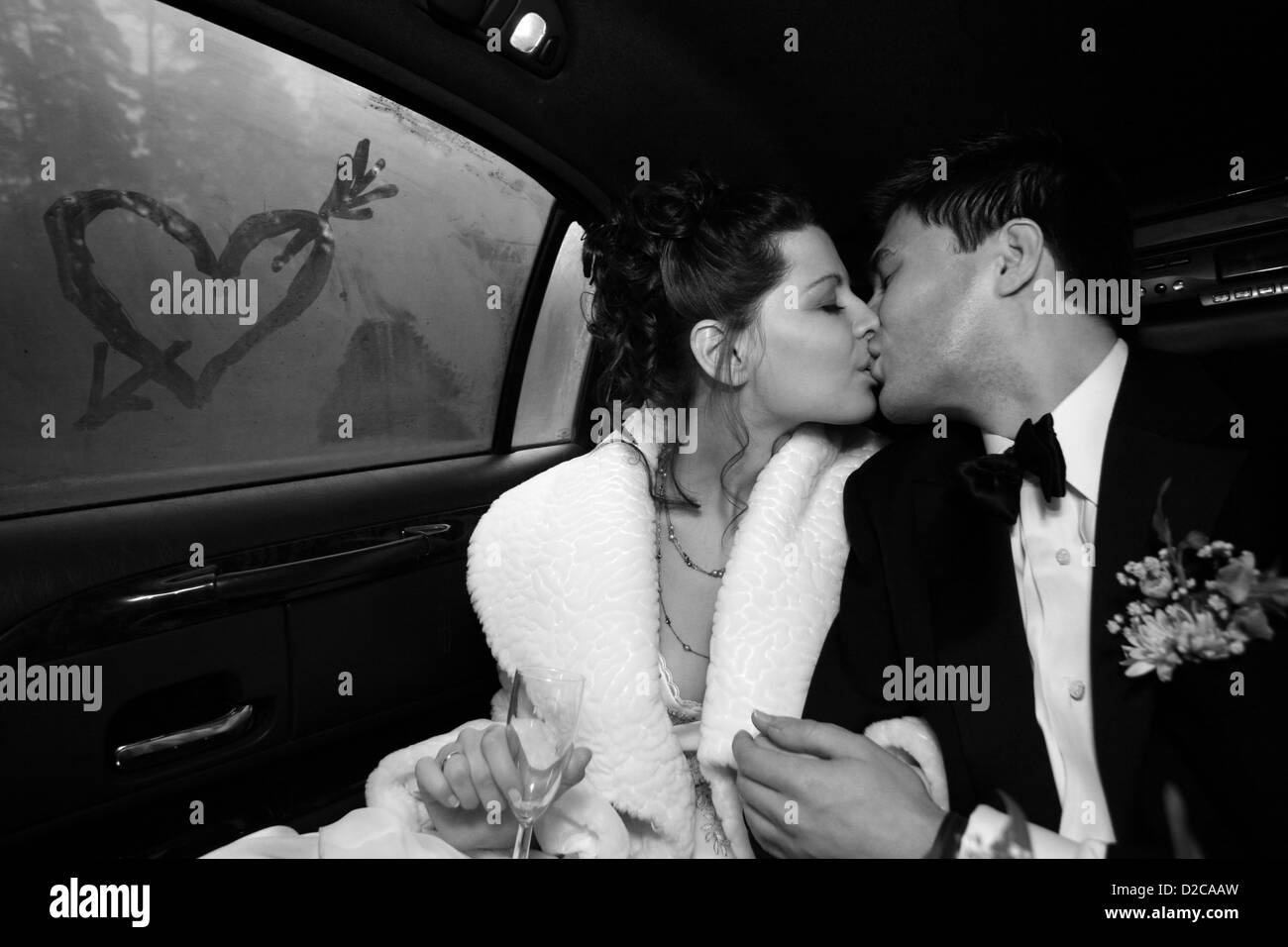Le marié et la mariée baiser dans la voiture. Sur glass heart est tiré. b/w Banque D'Images