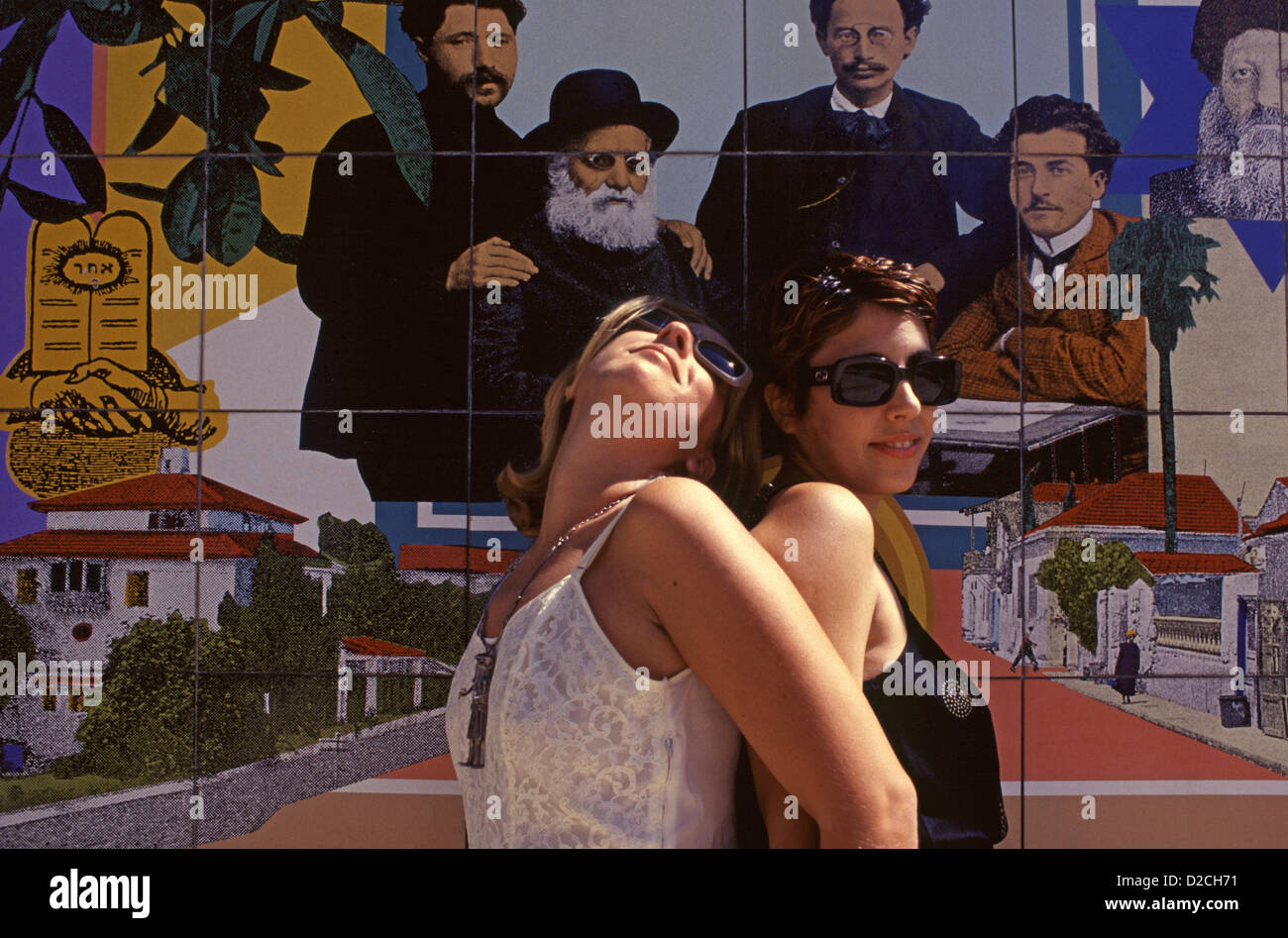 De jeunes femmes israéliennes posant devant la mosaïque murale par l'artiste et graphiste israélien David Tartakover, représentant l'histoire du quartier de Neve Tzedek dans la cour du Centre Suzanne Dellal pour la danse et le théâtre dans le quartier de Neve Tzedek, situé dans le sud-ouest de tel Aviv, Israël Banque D'Images