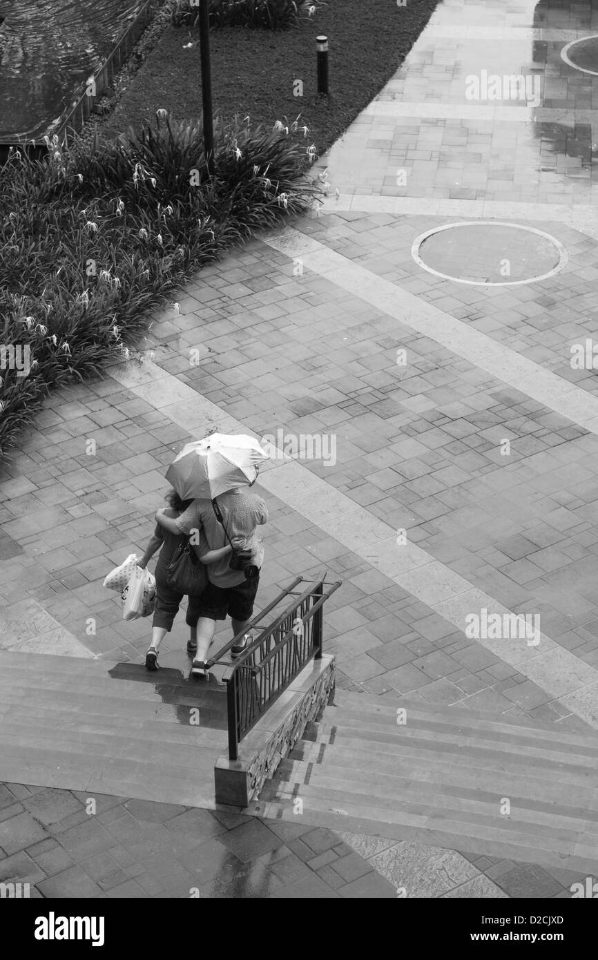 Deux promenades dans la pluie avec un parapluie. Banque D'Images