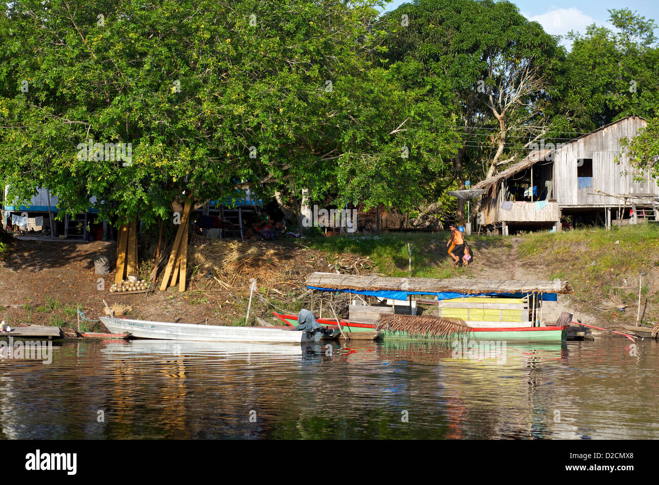 Village riverain le long de la rivière Amazone avec des maisons traditionnelles en bois, des bateaux colorés, un environnement de jungle luxuriante Banque D'Images