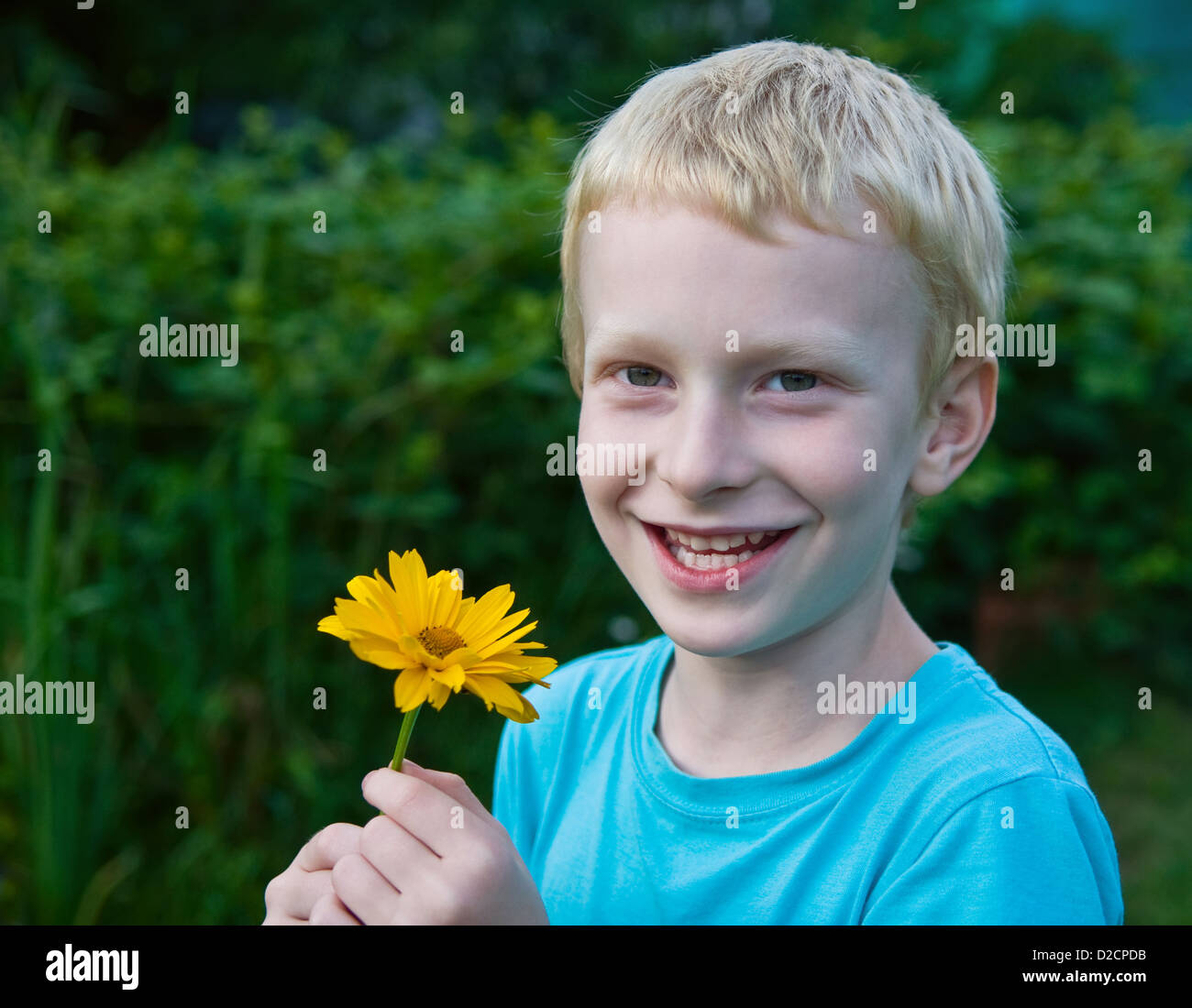 Cute blonde boy avec une fleur Banque D'Images