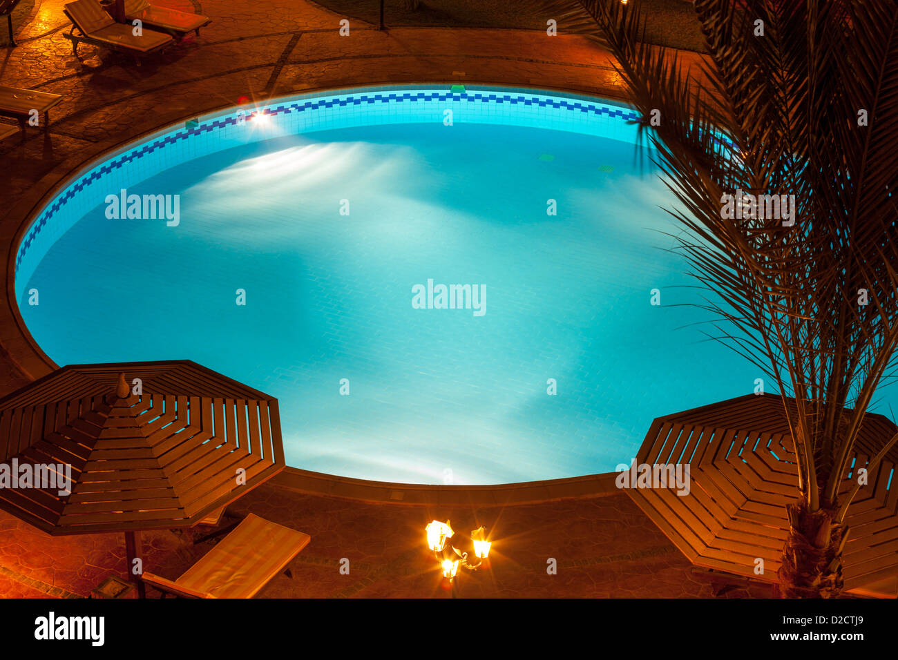 Une vue nocturne d'une villa de luxe de la piscine avec des parasols et des tables Banque D'Images