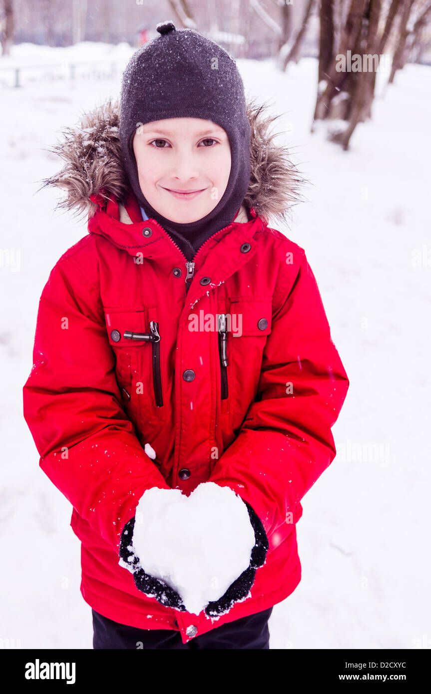 Smiling boy wearing red jacket holding heart Banque D'Images
