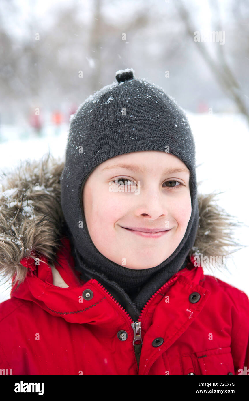 Smiling boy wearing red jacket dans snow park Banque D'Images