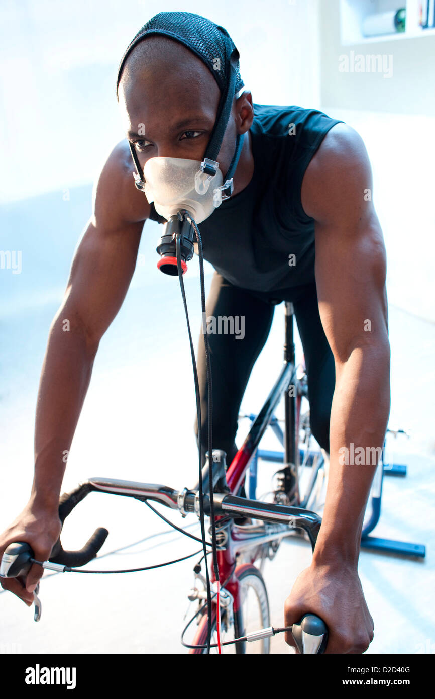 Les tests de performances de parution du modèle sportif équitation un vélo d'exercice alors que son rendement et la consommation d'oxygène sont mesurées Banque D'Images