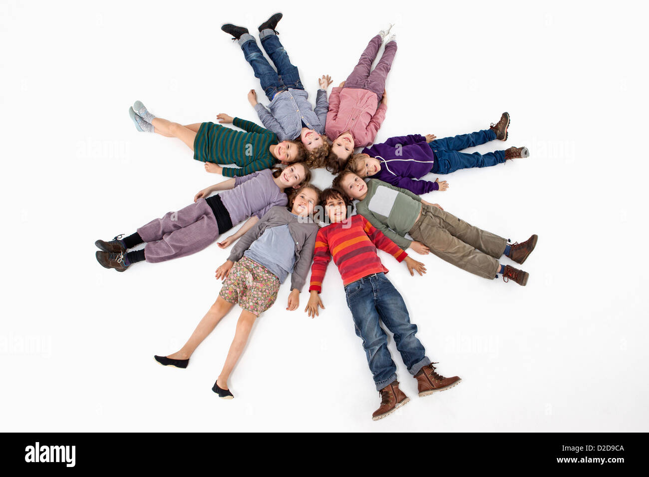 Un groupe d'enfants couchés sur le dos dans un cercle Banque D'Images