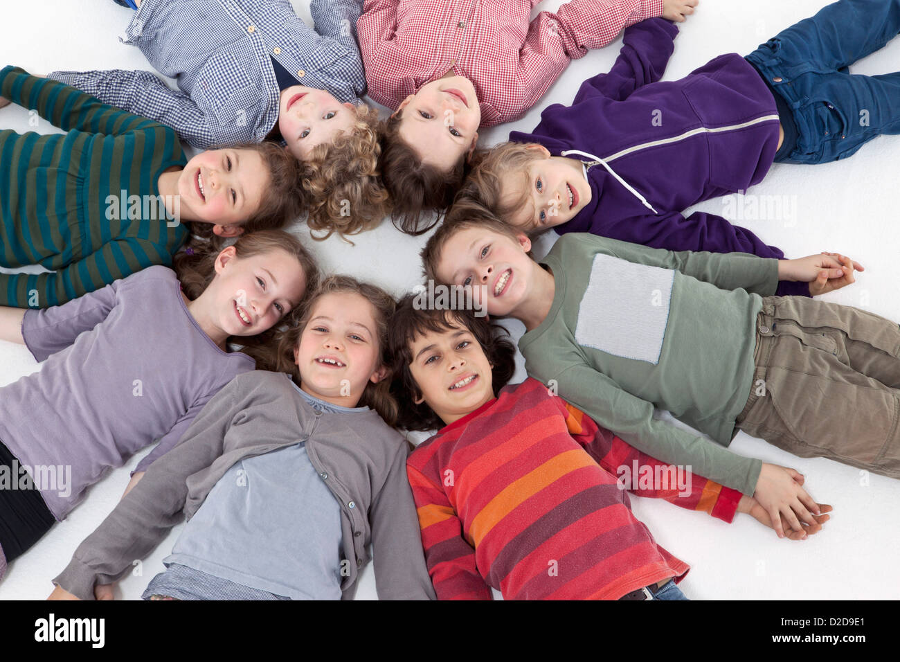Un groupe d'enfants couchés sur le dos dans un cercle, les chefs de toucher Banque D'Images