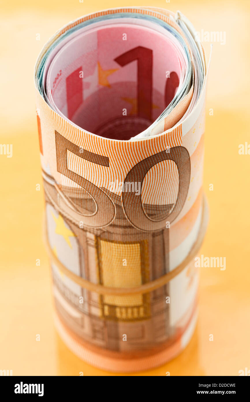 50 Euros remarque sur un rouleau de l'Euro zone euro currency roulées avec une bande élastique sur un fond d'or. L'UE l'Europe Banque D'Images