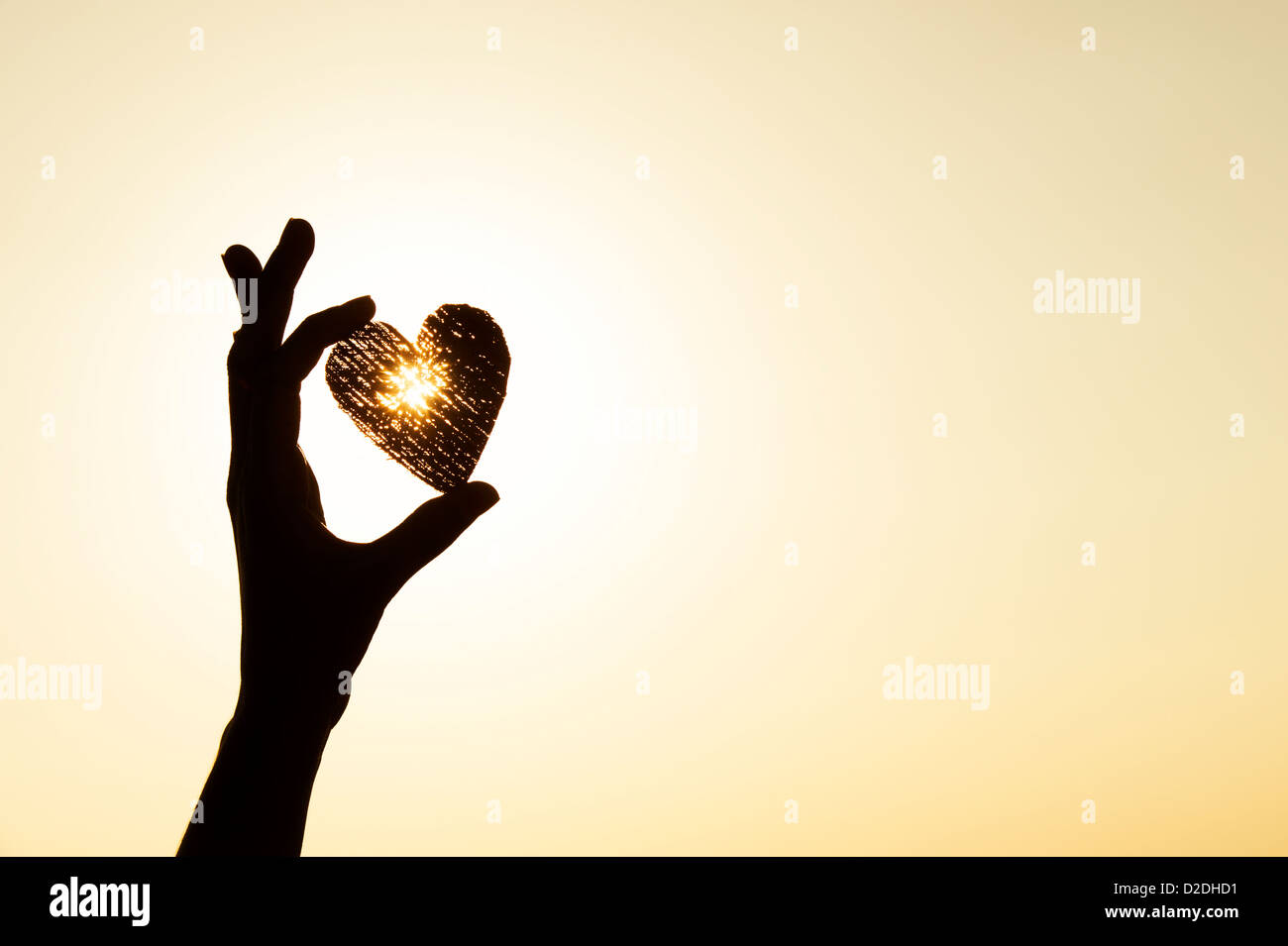 Les filles hand holding heart shape au coucher du soleil. Silhouette Banque D'Images