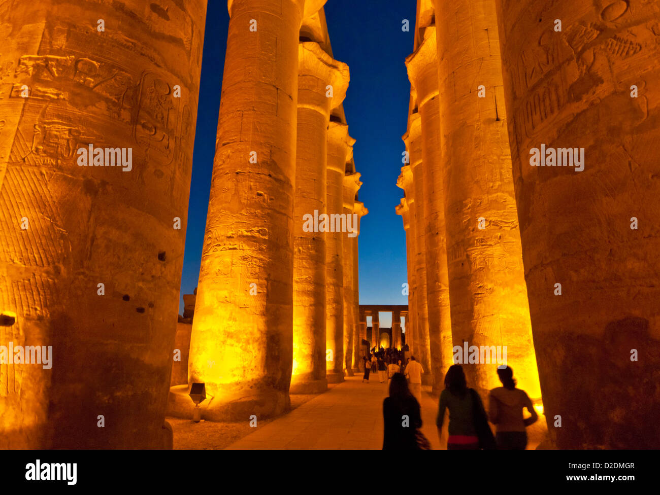Les touristes marcher parmi les courts de colonnes de la cour d'Amenhotep III du temple de Louxor Louxor au coucher du soleil l'Egypte Moyen Orient Banque D'Images
