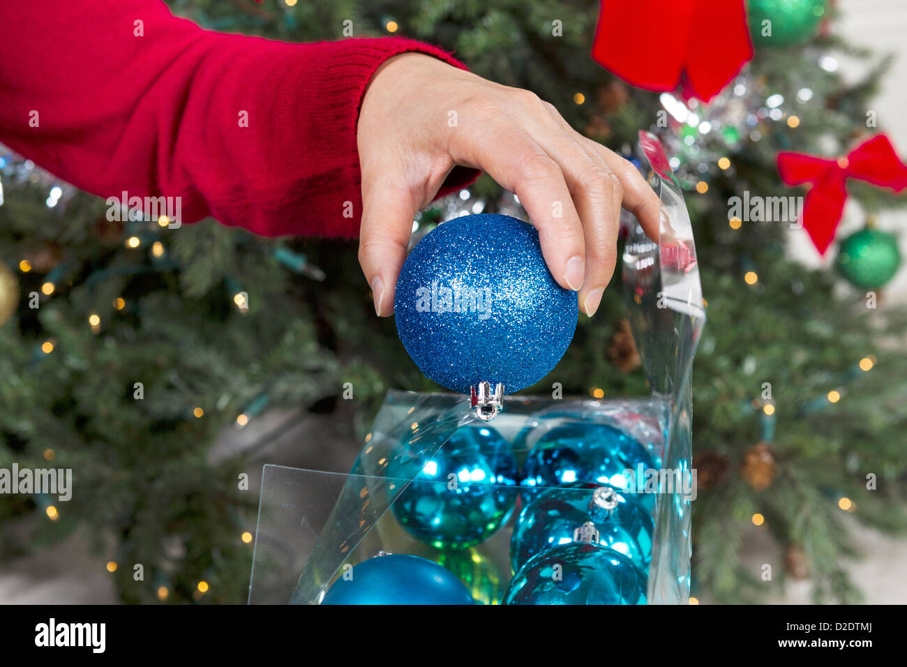 À main de femme ornements de vacances pour mettre fin à la saison à l'arbre de Noël en arrière-plan Banque D'Images