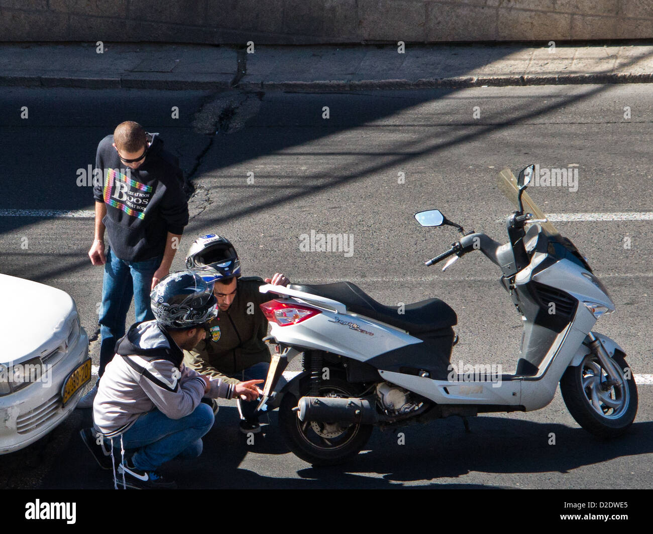 Trois jeunes conducteurs vérifier les dommages après une collision entre une voiture et une moto Banque D'Images