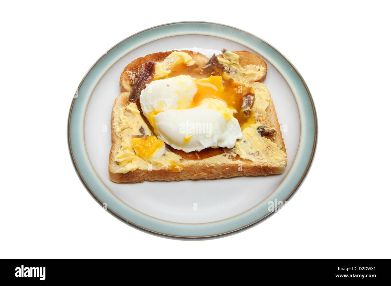Oeuf poché sur toast avec du beurre d'anchois sur une plaque isolés contre white Banque D'Images