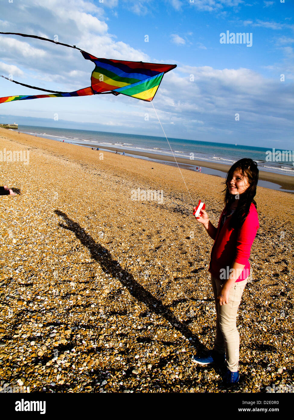 Jeune fille avec des cerf-volant sur la plage de galets Banque D'Images