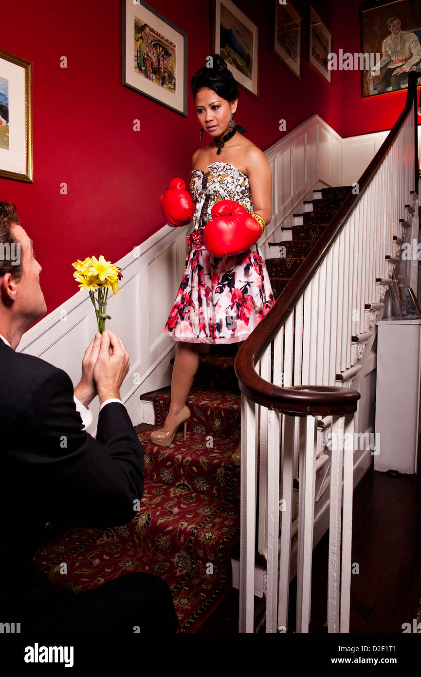 Man accueil fleurs à une femme portant des gants de boxe impliquant le pardon Banque D'Images