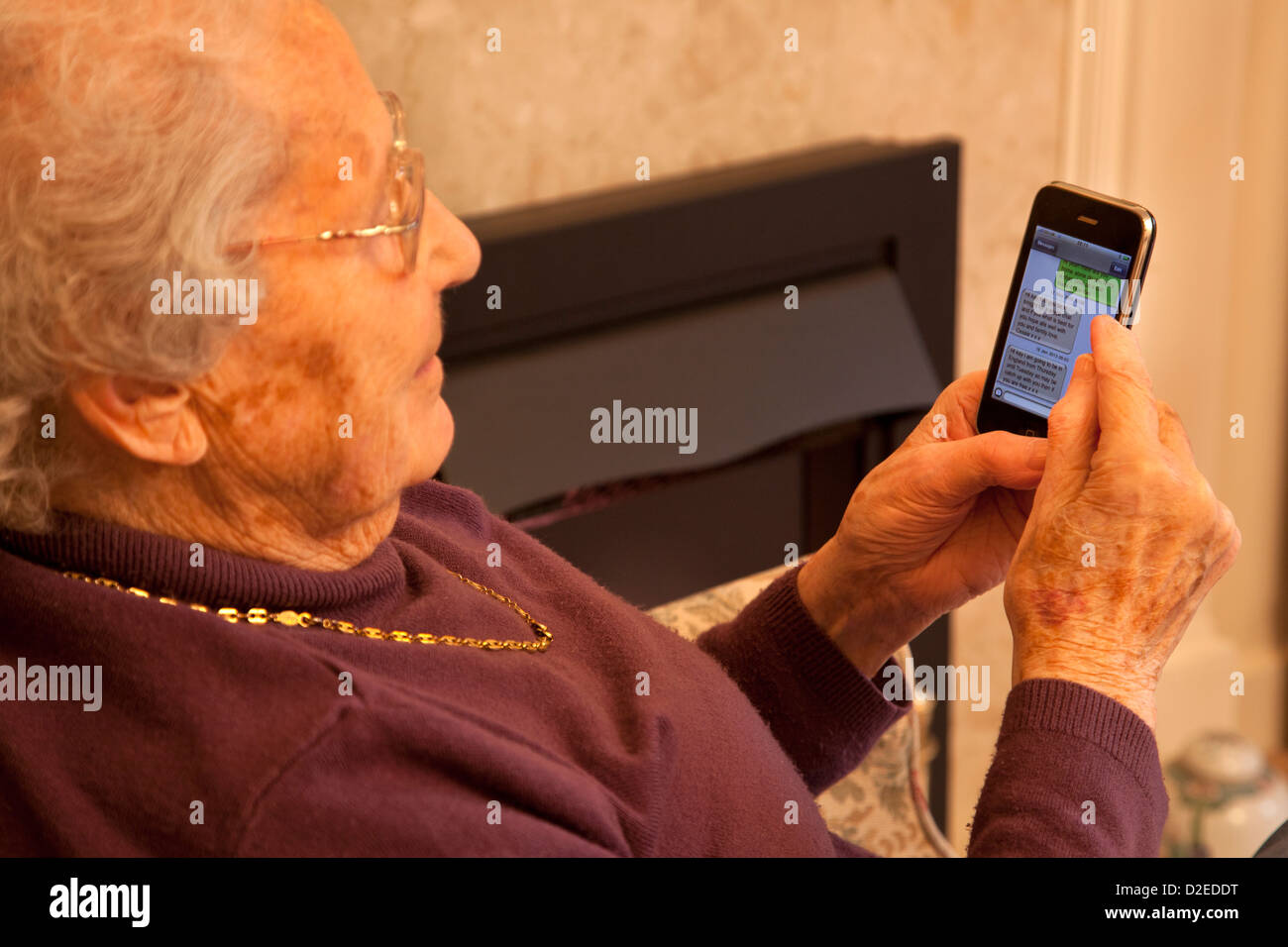 Une vieille dame âgée de taper un sms sur un iphone à puce Banque D'Images