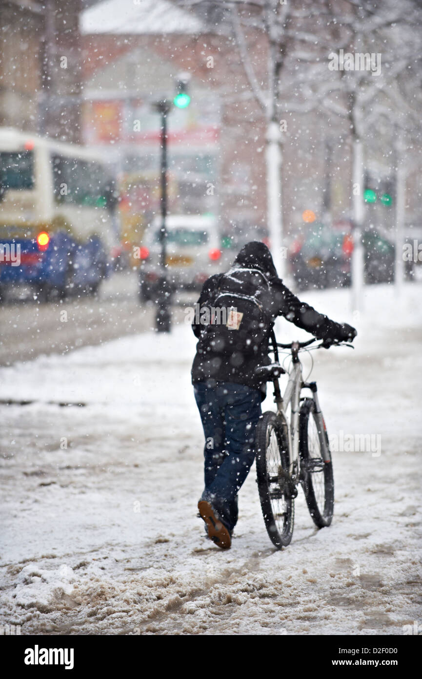 Man pushing bike à travers la neige en dehors de Belfast City Hall Banque D'Images