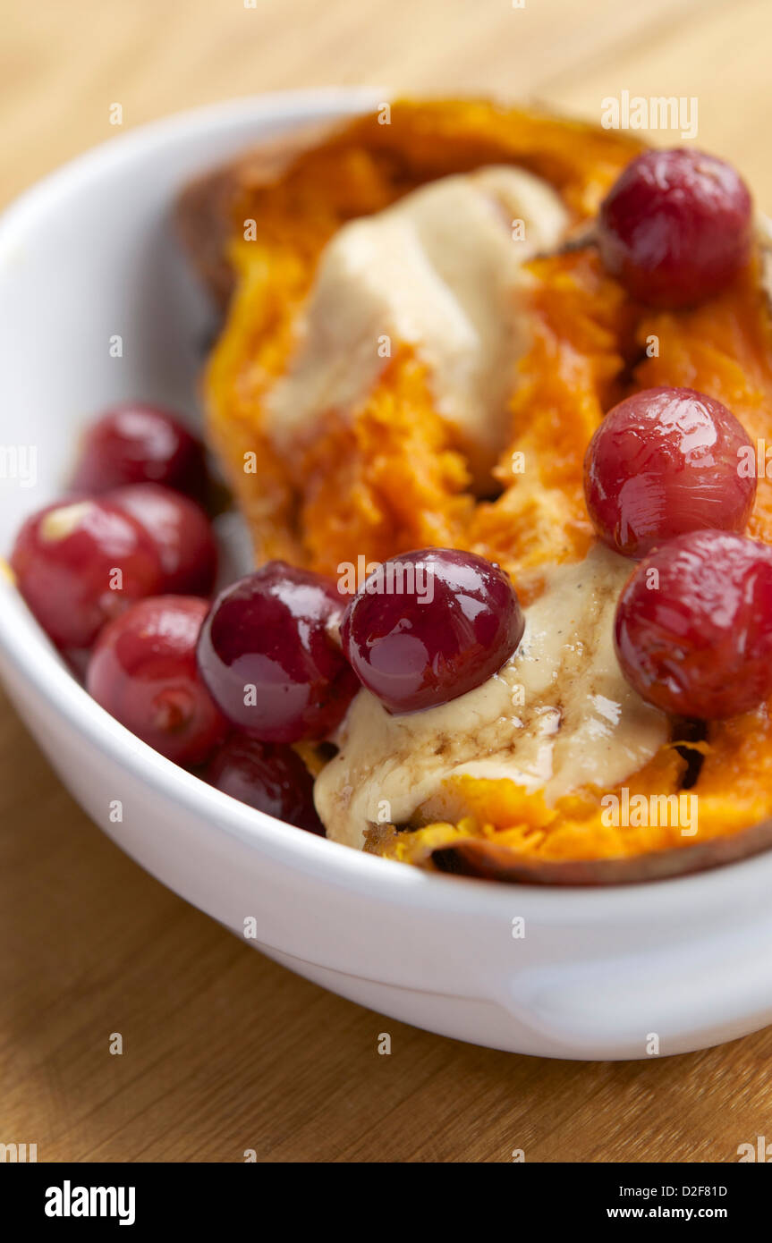 Bol avec patates douces rôties rempli de raisins avec une sauce au fromage vegan et sirop d'érable Banque D'Images