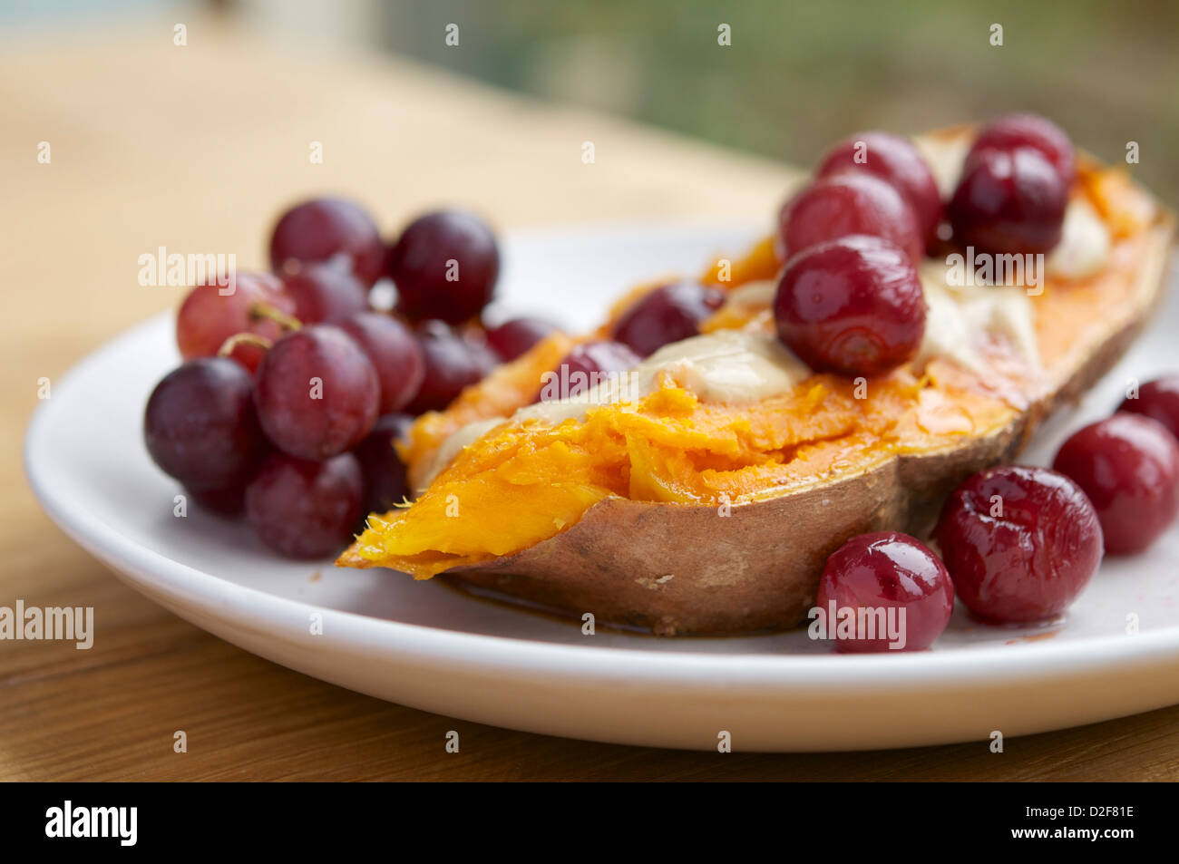 La plaque avec des patates douces rôties rempli de raisins avec une sauce au fromage vegan et sirop d'érable Banque D'Images