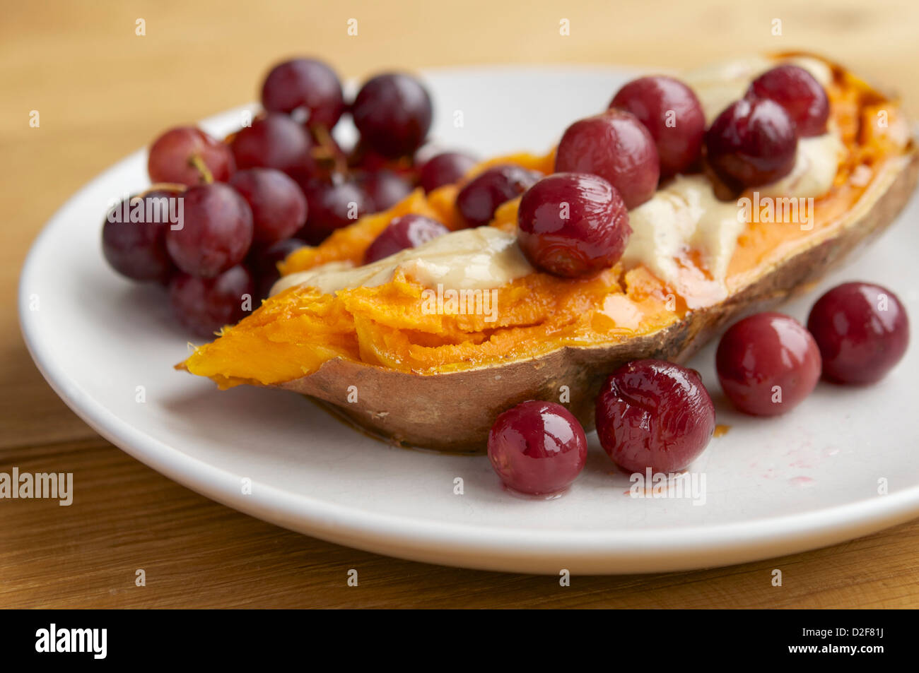 La plaque avec des patates douces rôties rempli de raisins avec une sauce au fromage vegan et sirop d'érable Banque D'Images