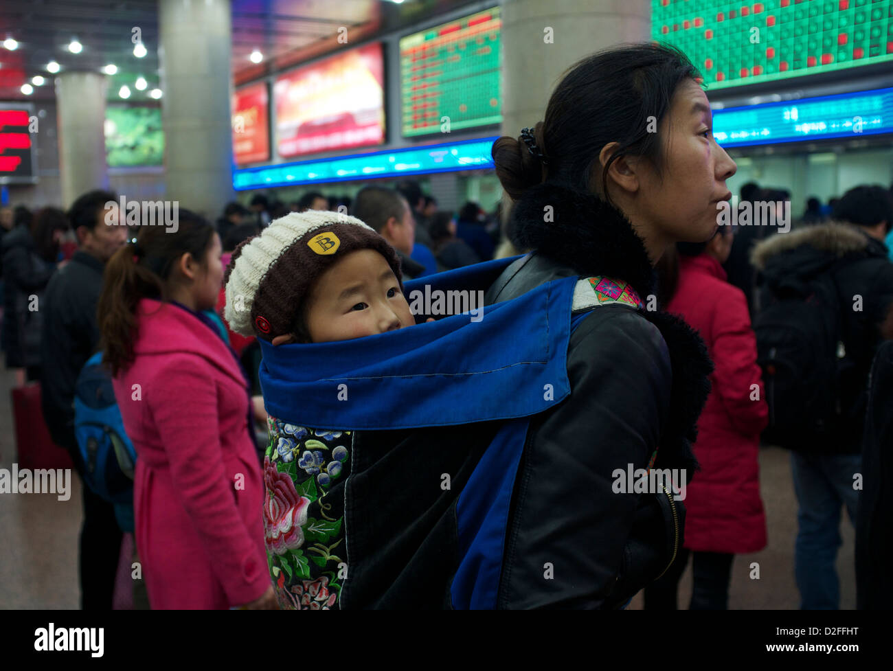 Une mère chinoise tenant un bébé sur son dos queue pour acheter des billets de train à la gare de Pékin, Chine. 22-Jan-2013 Banque D'Images