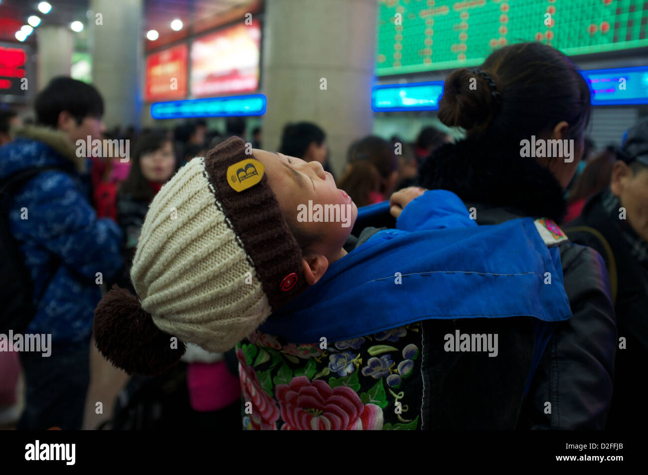 Un bébé pleure pendant que sa mère queue pour acheter des billets de train à la gare de Pékin, Chine. 22-Jan-2013 Banque D'Images