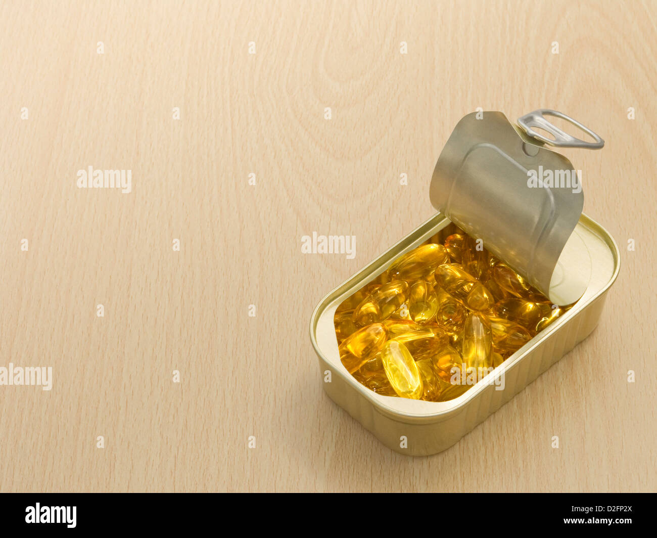 Des capsules d'huile de poisson dans un anneau fer-blanc sur la surface en bois Banque D'Images