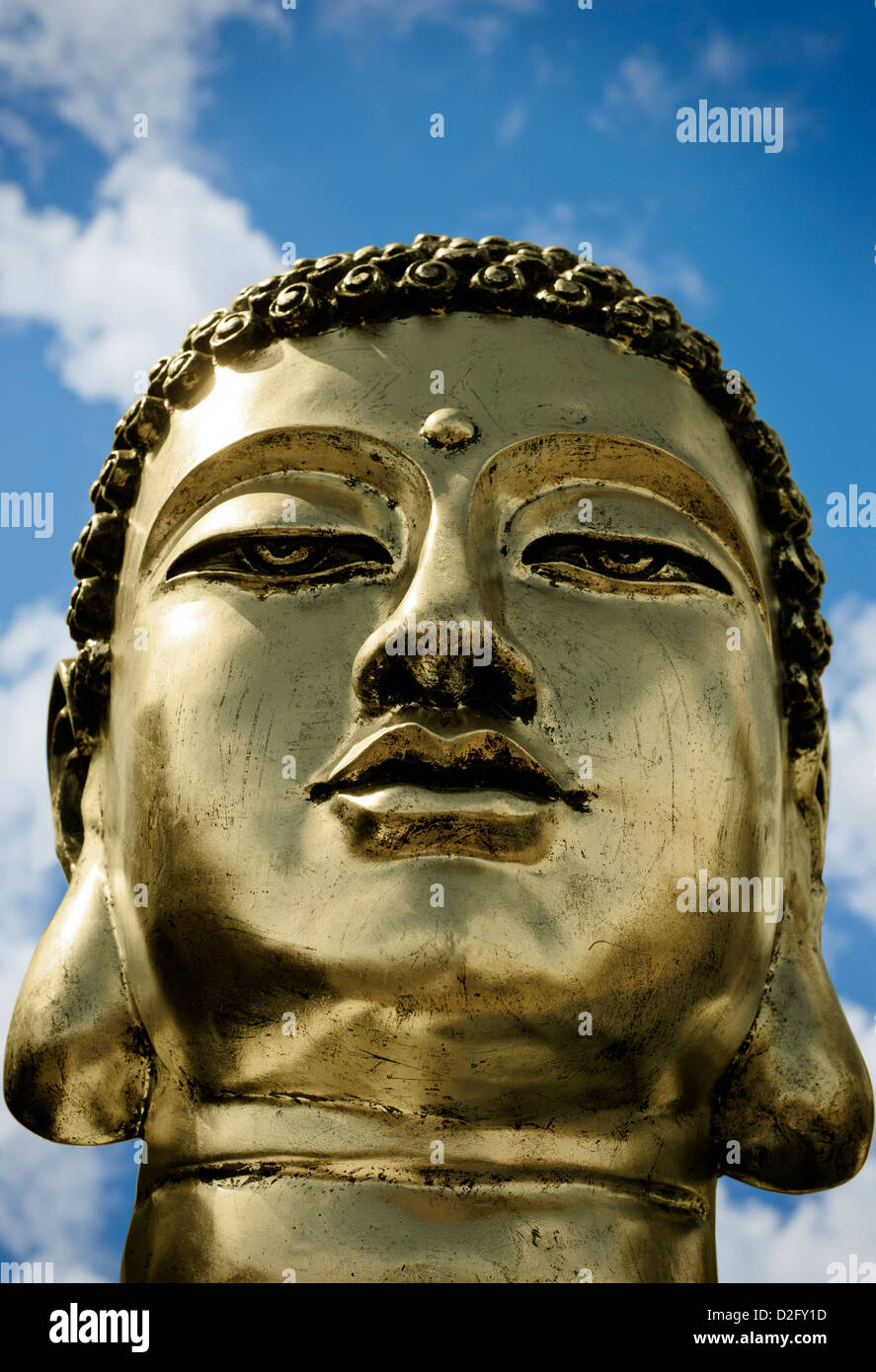 Close up detail d'un Bouddha en or tête contre un ciel nuageux ciel bleu Banque D'Images