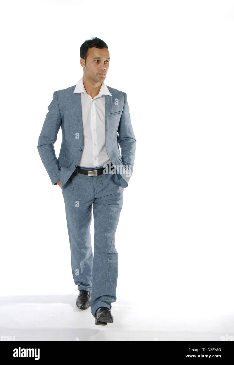 L'homme en costume avec les mains dans les poches, marchant vers la caméra. Habillée d'une légère chemise blanche à col ouvert. Banque D'Images