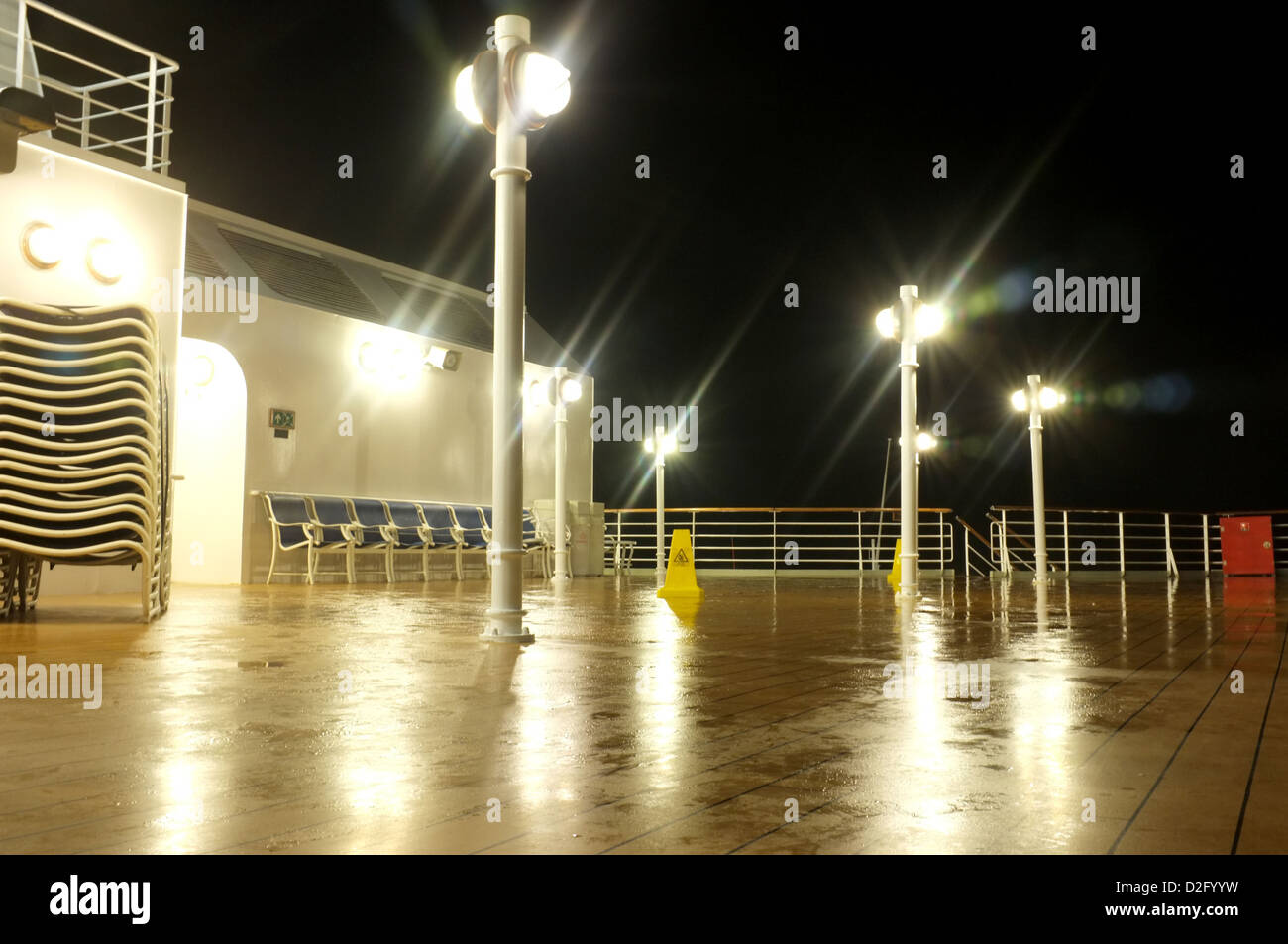 Dans l'obscurité de la nuit en mer, les lumières reflètent sur un pont extérieur humide de la Cunard, Queen Victoria Banque D'Images