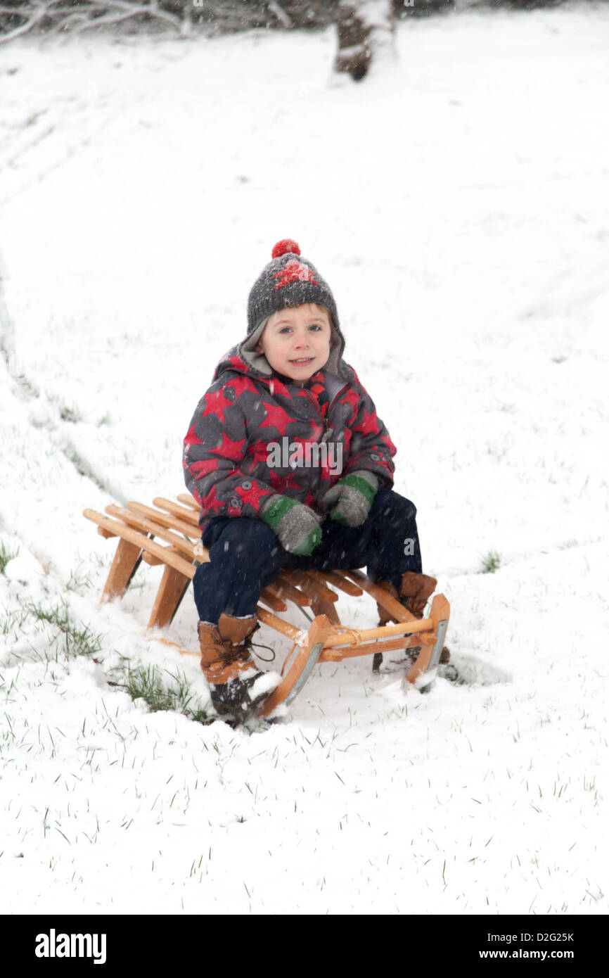 Trois ans à l'extérieur de jouer dans la neige sur un toboggan. Alresford Hampshire, Angleterre, Royaume-Uni. Banque D'Images