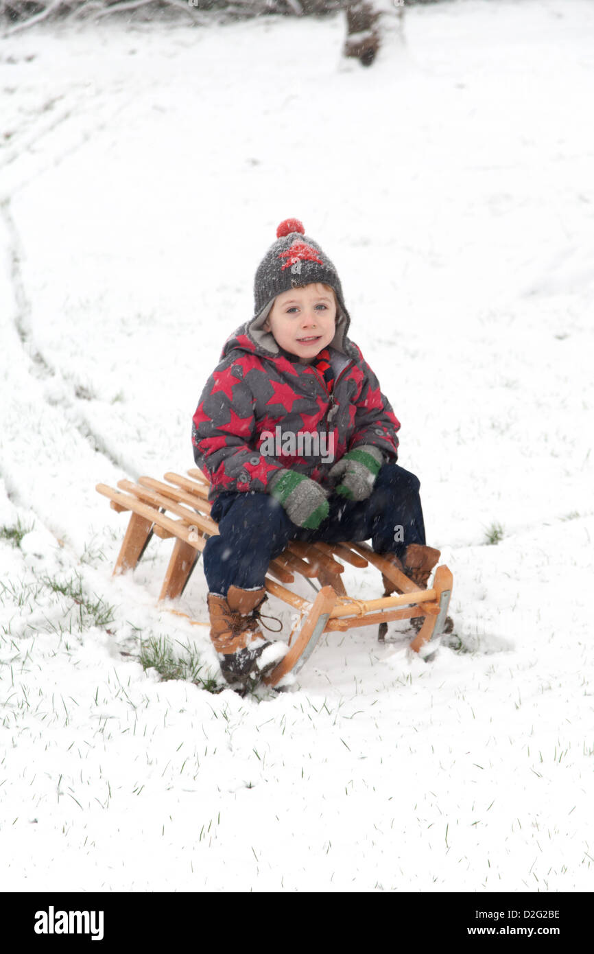 Trois ans à l'extérieur de jouer dans la neige sur un toboggan. Alresford Hampshire, Angleterre, Royaume-Uni. Banque D'Images