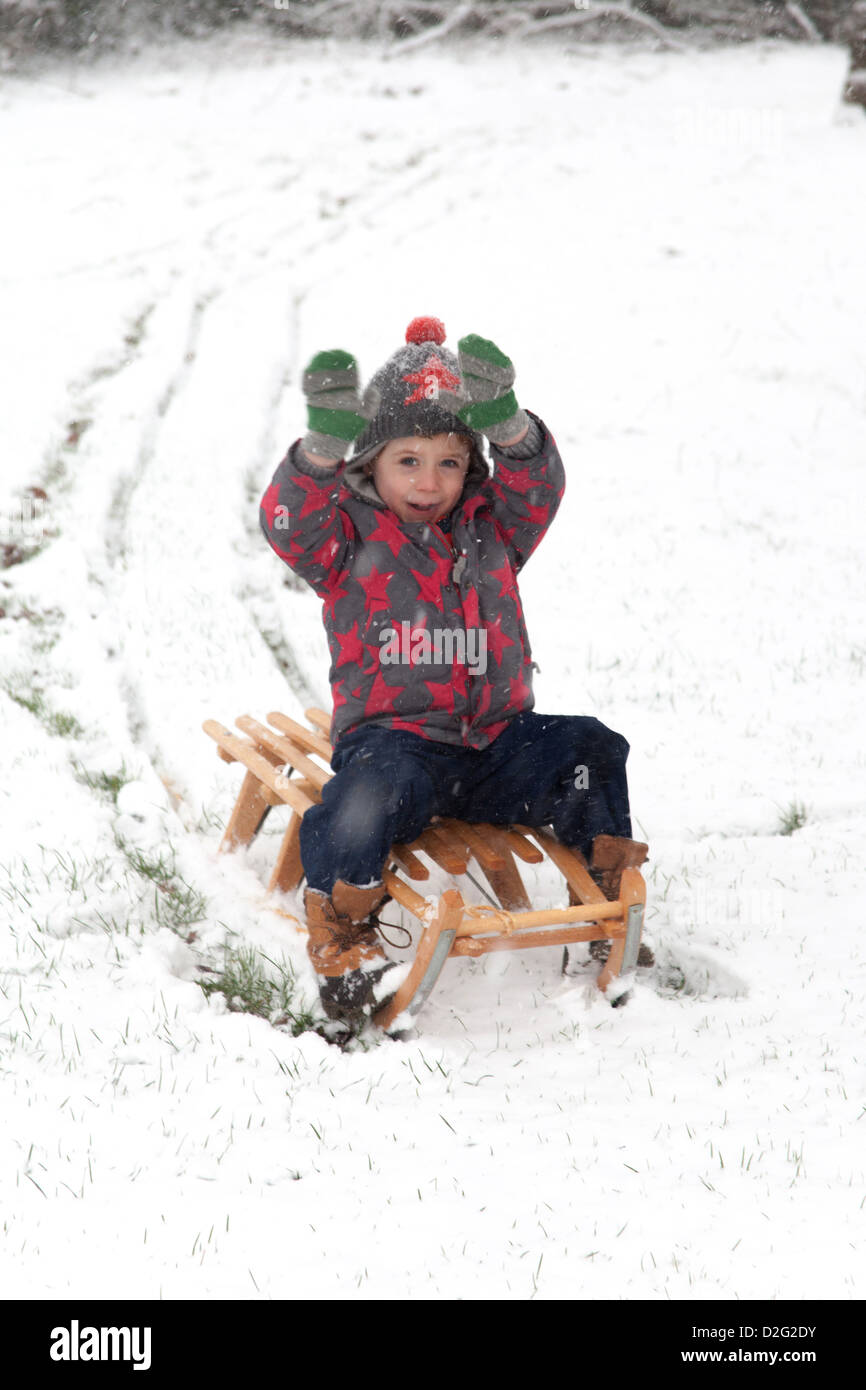 Trois ans à l'extérieur de jouer dans la neige sur un toboggan. Alresford Hampshire, Angleterre, Royaume-Uni. Banque D'Images