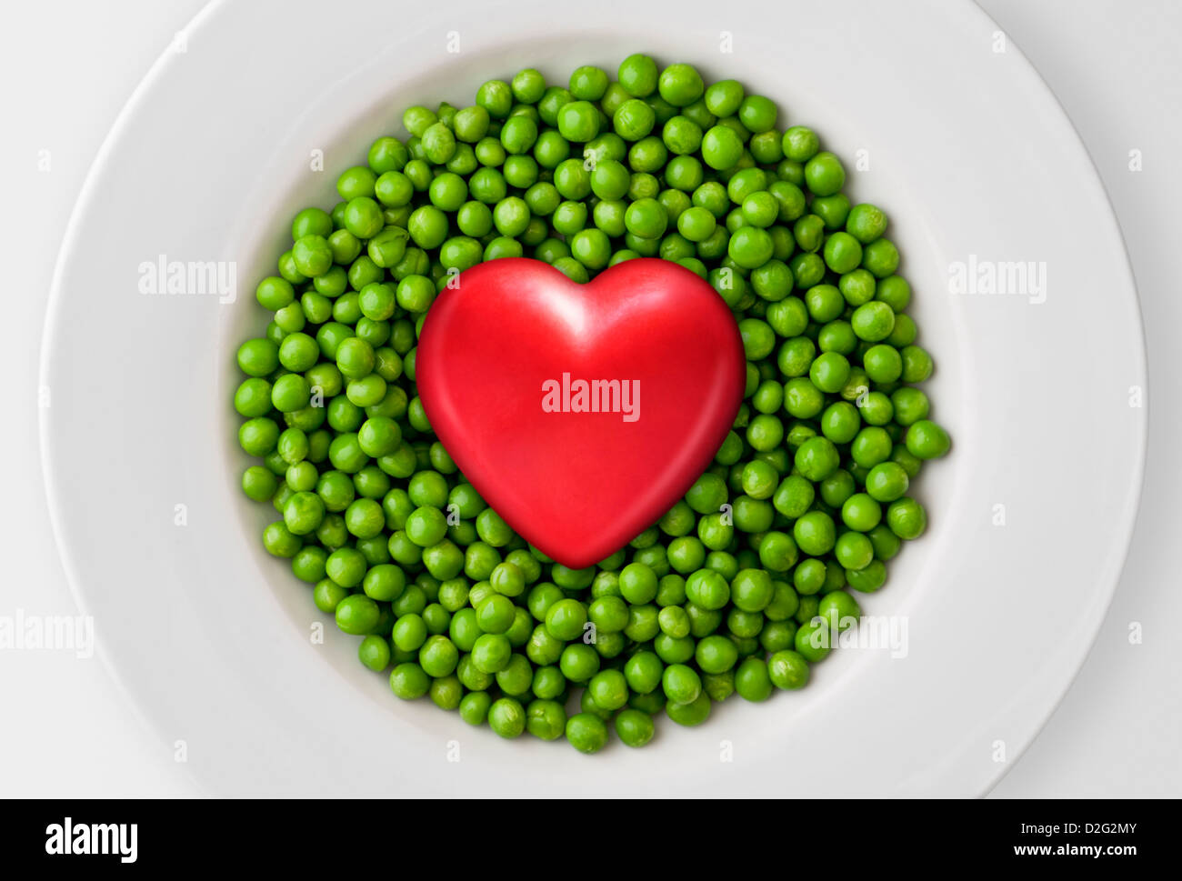 Concept d'aliments sains, un cœur rouge sur les pois verts frais Banque D'Images